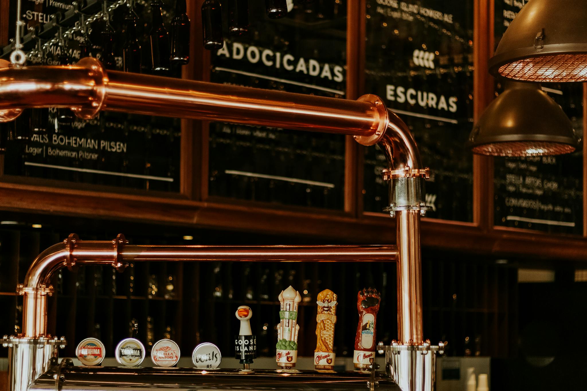 Close-up of a brewery taproom interior featuring copper pipes and beer taps. Ideal for beverage industry visuals.