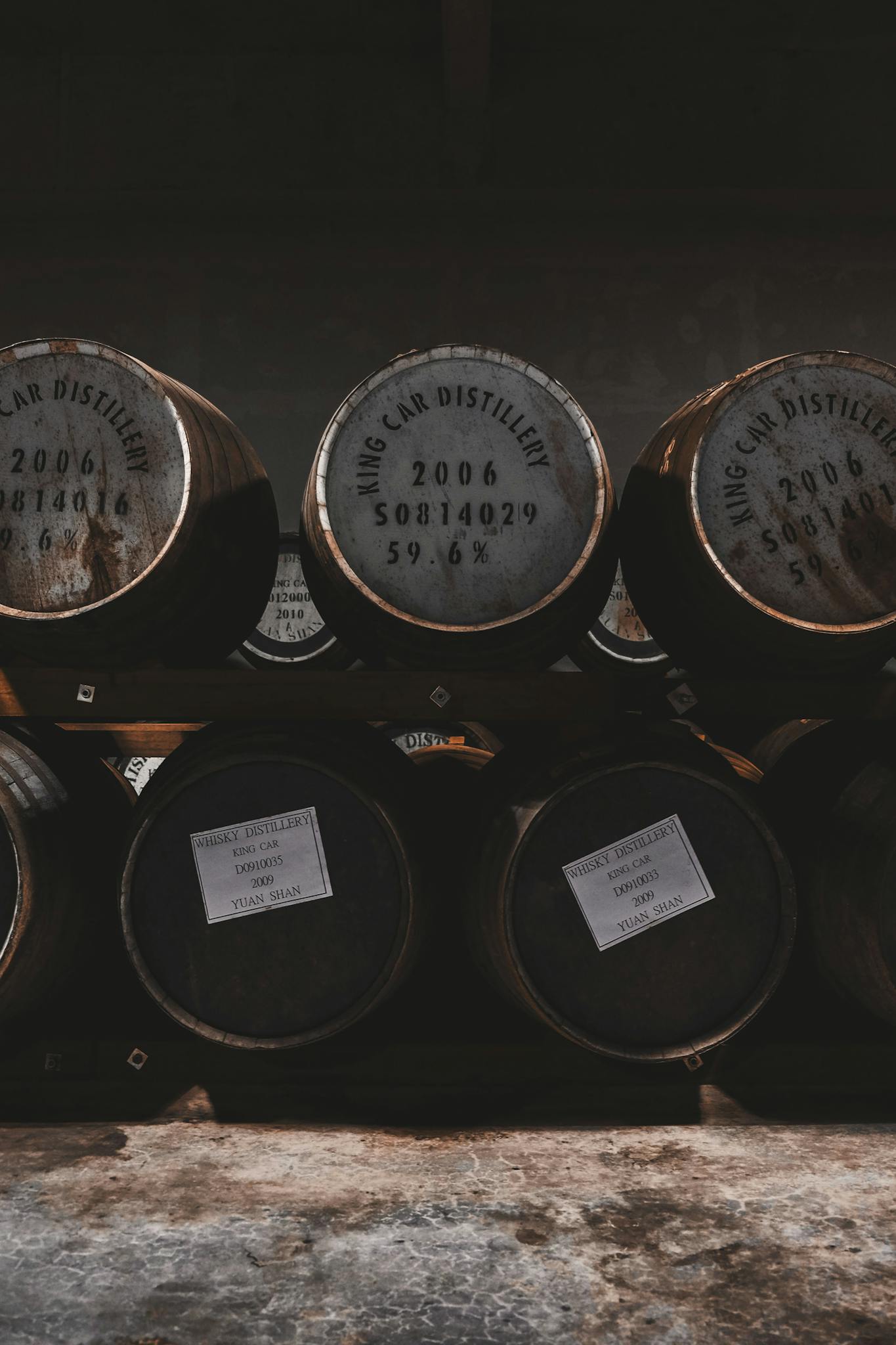 Row of vintage wooden barrels in a distillery storage room, showcasing aged casks and rustic ambiance.