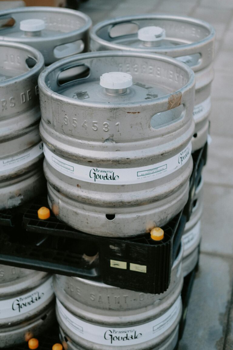 Close-up of stacked metal beer kegs in an outdoor industrial area.